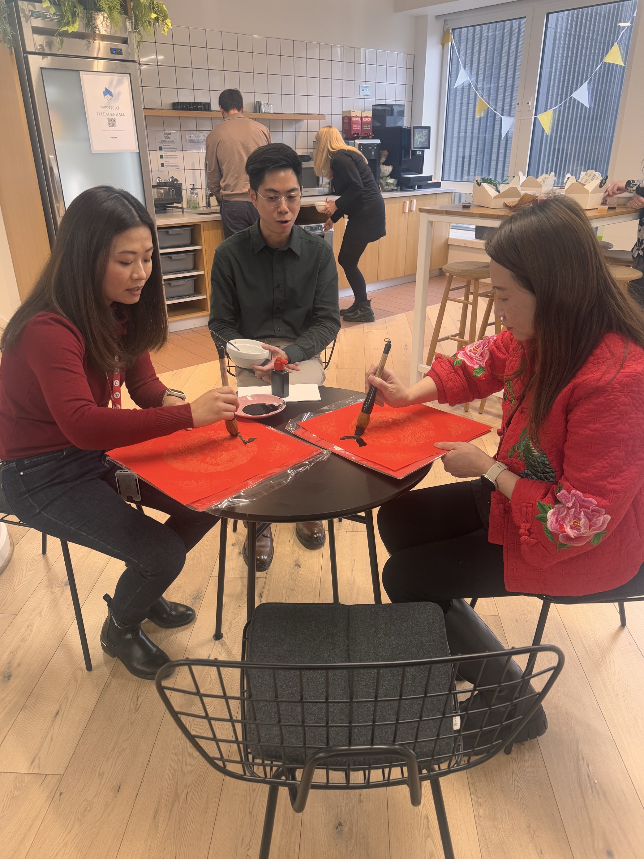 Three people sitting at a table painting